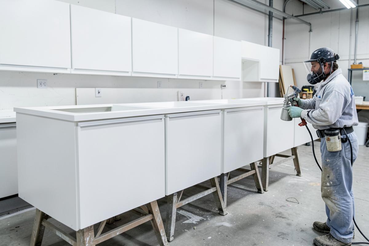 Professional spraying kitchen cabinet doors with a smooth factory-like finish in a workshop